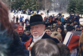 A dense group of people pressing around one figure in a light coat.